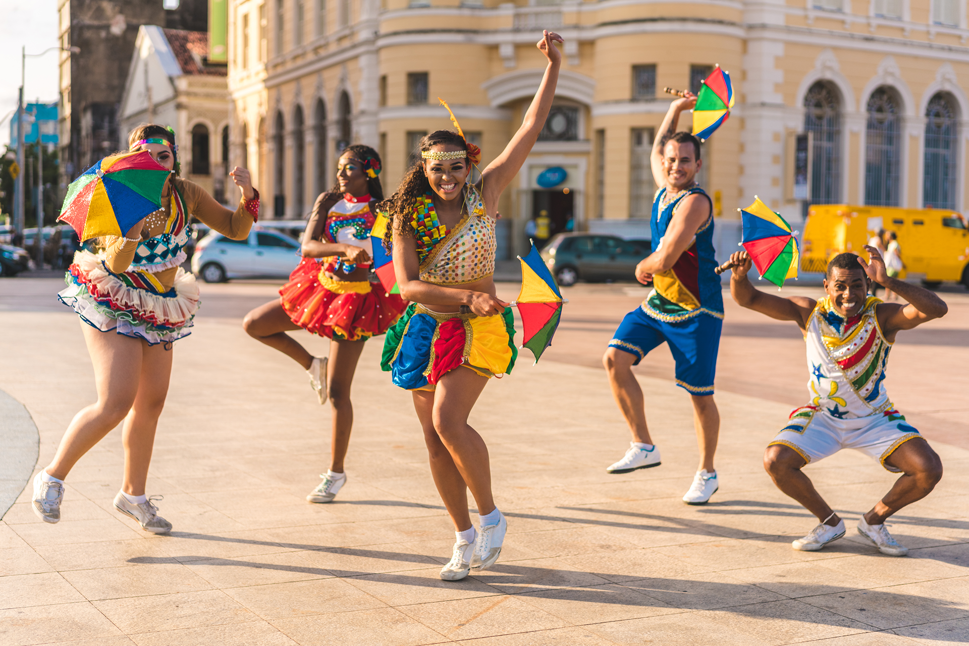 Dancers in colorful costumes holding umbrellas.