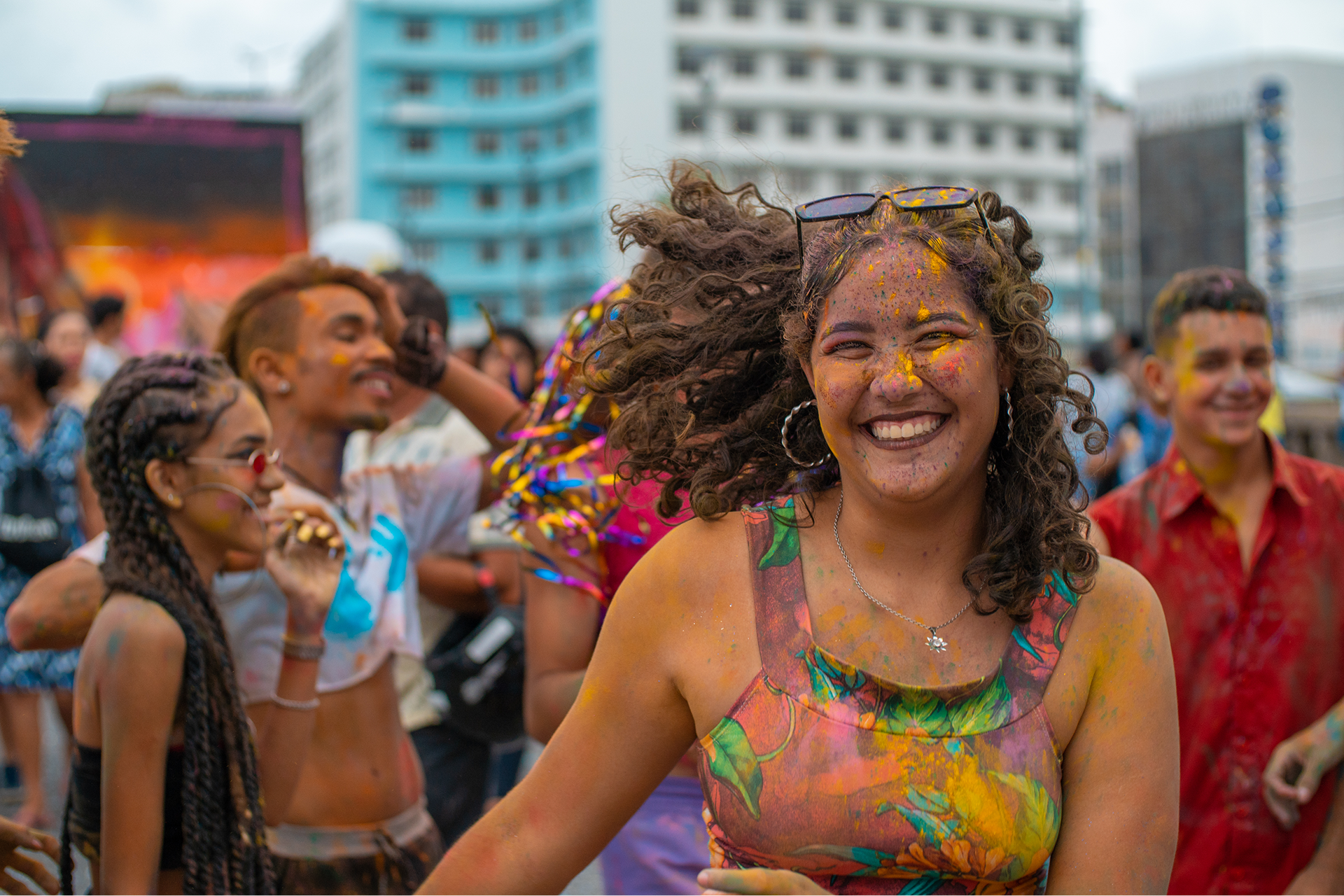 Smiling woman at colorful outdoor festival celebration.