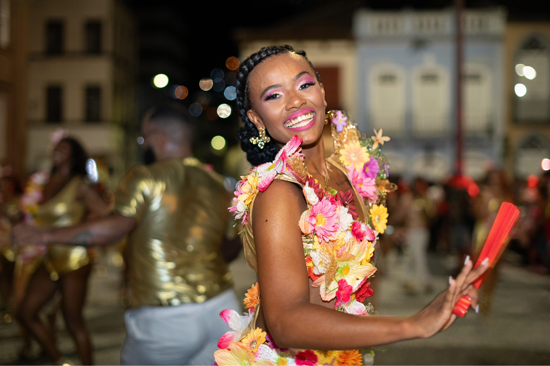 Smiling dancer in colorful floral costume at carnival.